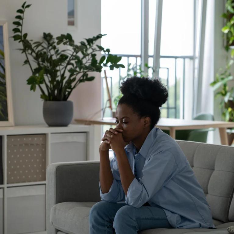 Oppressed African American woman with sad face sits on sofa thinking about future Life trouble